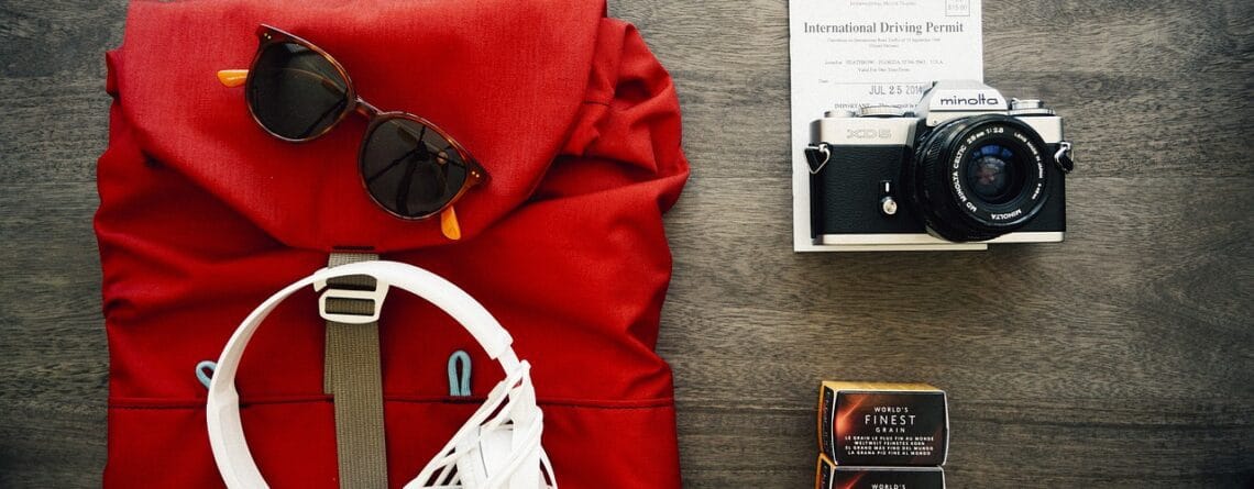 Flat lay of road trip essentials on wooden surface.