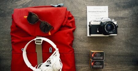 Flat lay of road trip essentials on wooden surface.