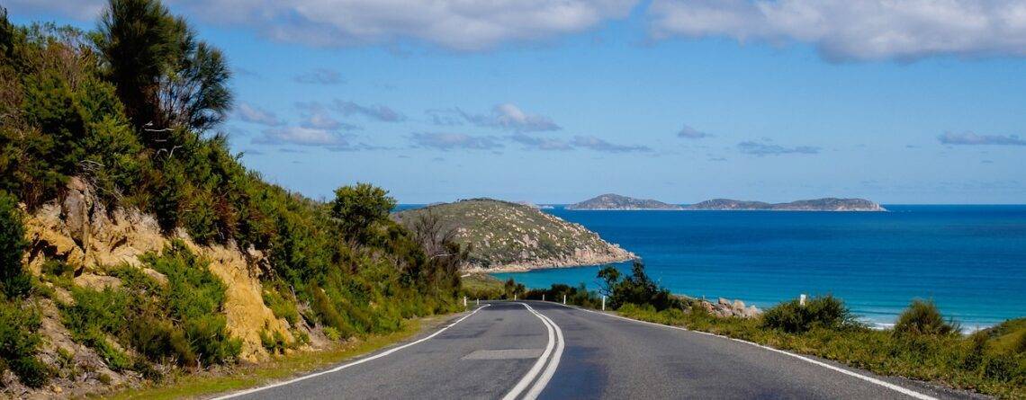 Winding coastal road with cliffs and ocean waves.