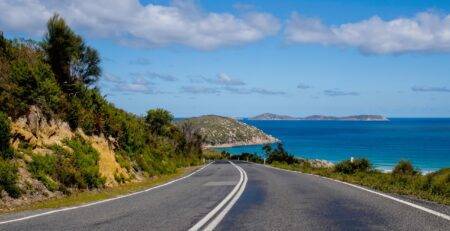 Winding coastal road with cliffs and ocean waves.