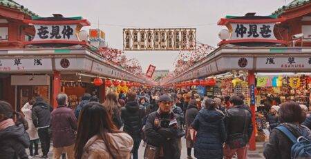 Crowds of tourists exploring Nakamise Shopping Street in Asakusa, Tokyo, Japan with traditional shops and decorations leading to Sensoji Temple