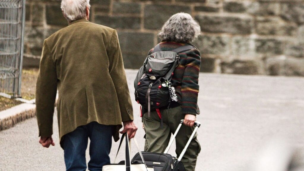 a man and a woman walking down the street with luggage