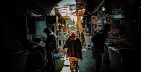 Traditional market street in Morocco with locals walking through a narrow souk, representing everyday life and travel safety in Morocco