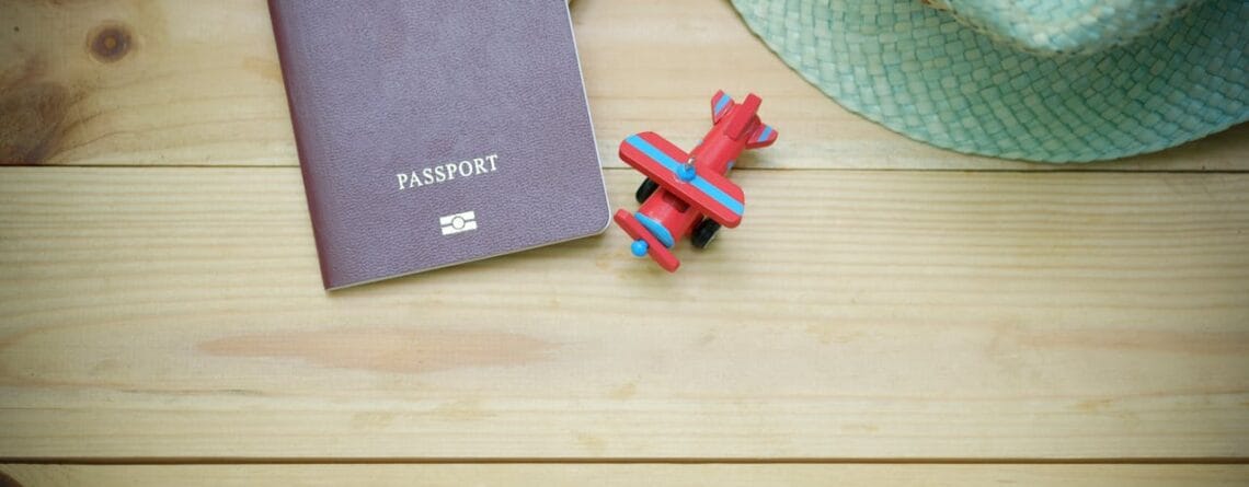 A brown passport next to a toy airplane on a wooden background, representing Schengen travel insurance requirements for 2026.
