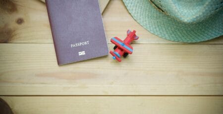 A brown passport next to a toy airplane on a wooden background, representing Schengen travel insurance requirements for 2026.
